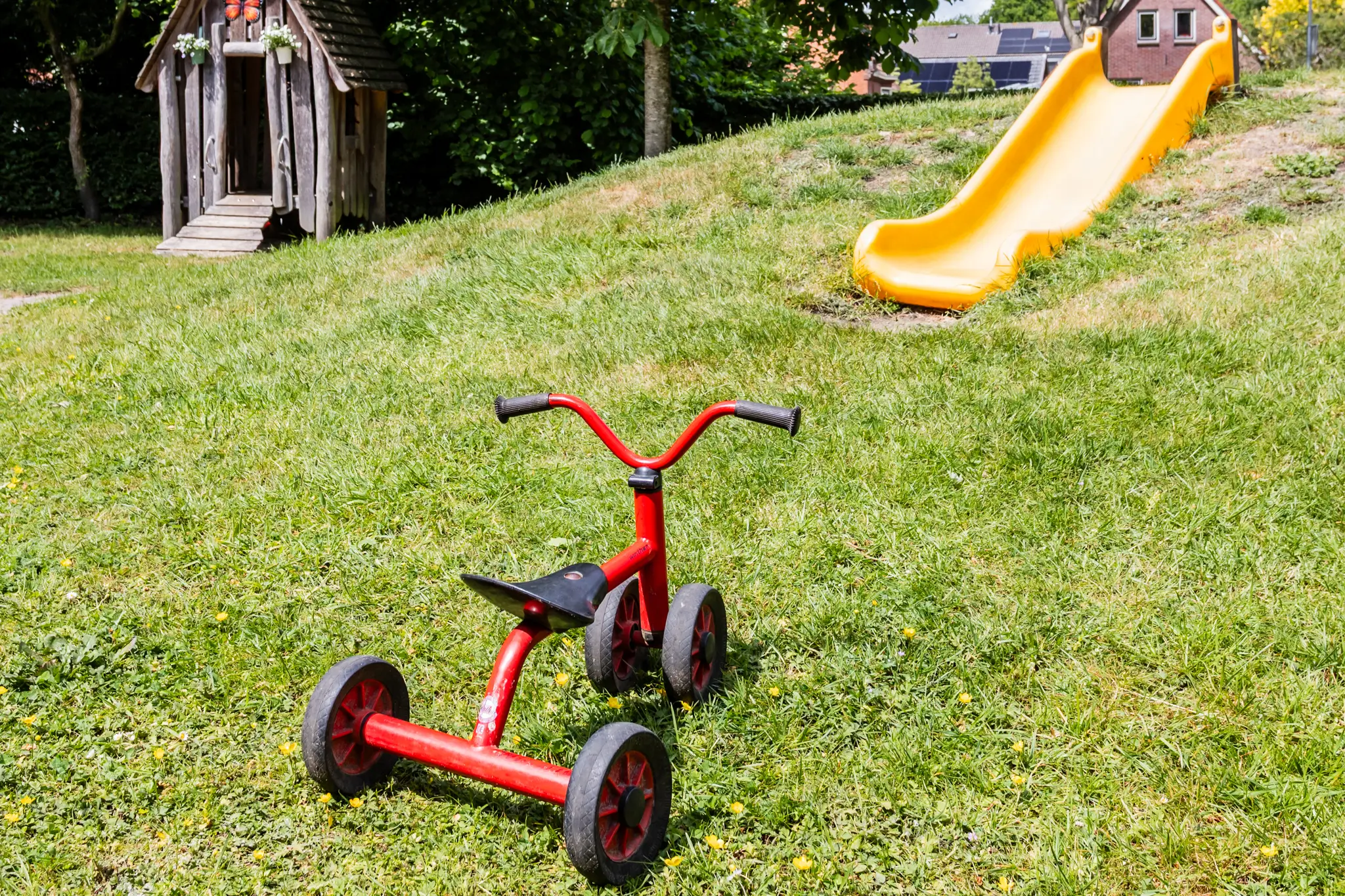 Liedekeijn tuin kdv spelen Tuin van kinderdagverblijf Liedekeijn met glijbaan, houten huisje en rode fiets
