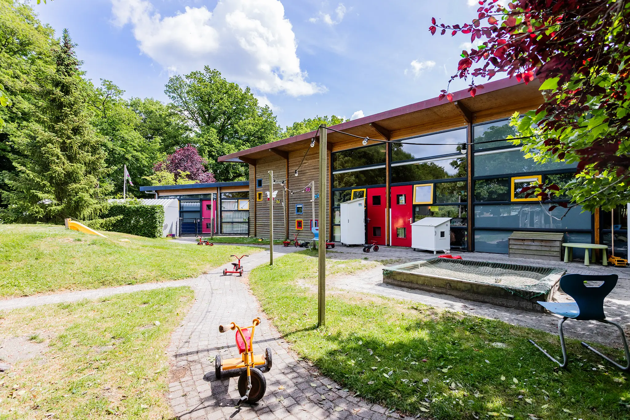 Liedekeijn achter Buitenruimte bij kinderdagverblijf LLiedekeijn met zandbak, glijbaan en speelgoed
