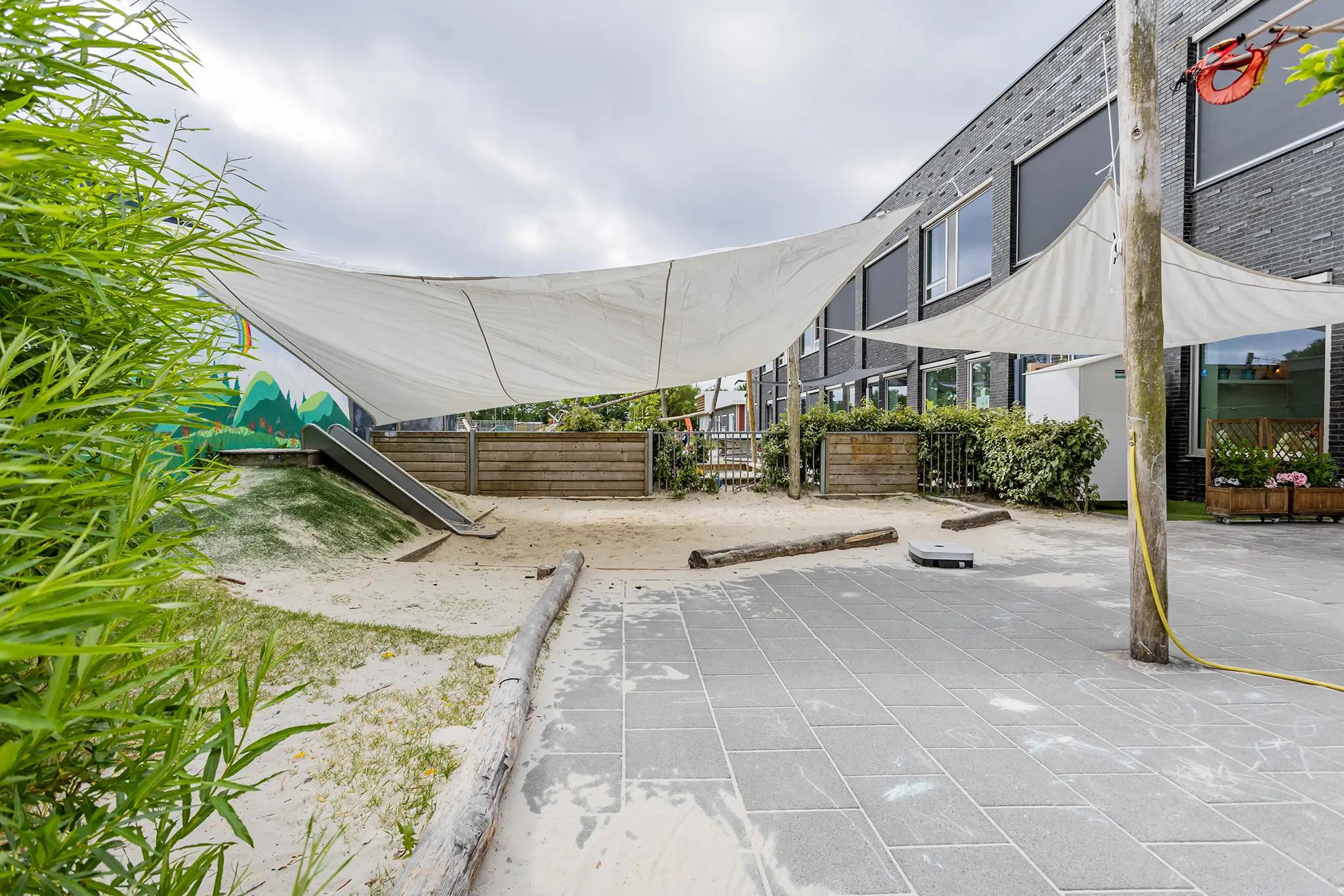 Woelwaters II buiten zandbak met glijbaan De tuin van KDV Woelwaters II met glijbaan en zandbak bij CKC De Rietzanger